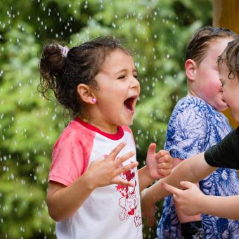 Little girl shouting with joy under water play rain drops